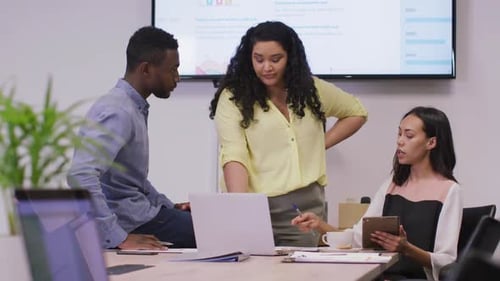 Happy diverse group of business people working together, using laptop in modern office