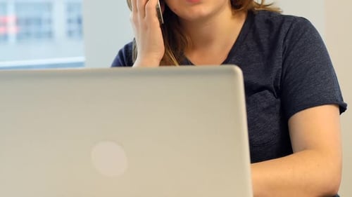 Woman on Phone Talking Near Laptop Indoors