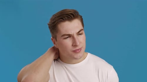 Man Massaging Stiff Neck From Pain Against Blue