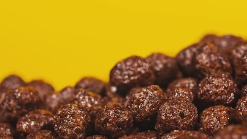 Chocolate Cereal Balls on Yellow Background Close Up