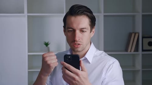 Enthusiastic man celebrating success using his cellphone