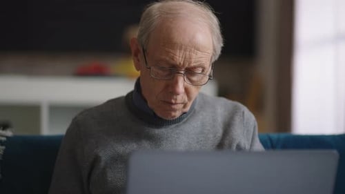 Old Wrinkled and Bald Man is Working in His Home Office Portrait of Male Retiree in Apartment Using