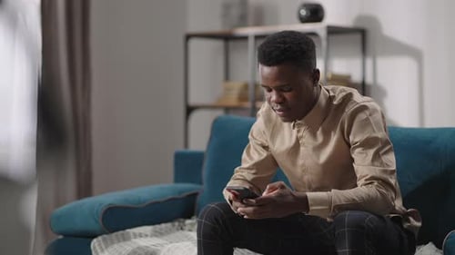Young Adult Using Smartphone on Couch at Home