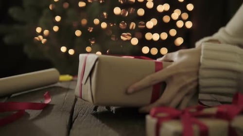 Woman Tying Red Ribbon on Christmas Gift