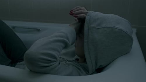 Person in Bathtub with Hands Covering Face