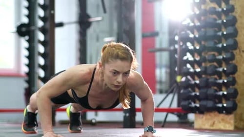 A Sporty Girl Performs Pushups From the Floor in the Gym
