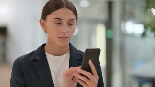 Young Woman Uses Mobile Phone in Business Setting