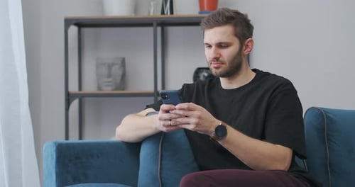 Man Relaxing on Couch Using Cell Phone