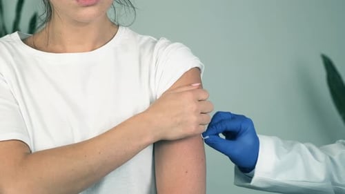 Doctor Giving Young Adult Injection in Upper Arm