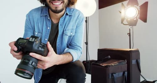 Smiling Photographer Holding Camera in Bright Studio