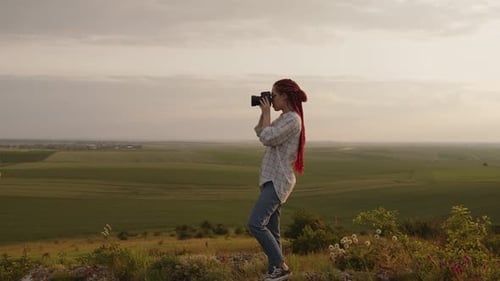 Woman Taking Photos on Hill at Sunset