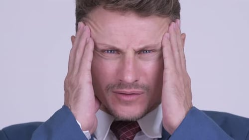 Man in Suit Holding Head in Pain