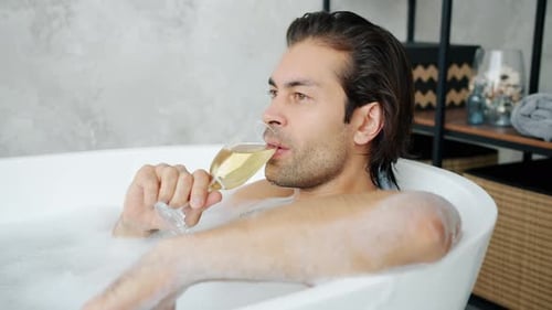 Man Relaxing in Bubble Bath with Champagne
