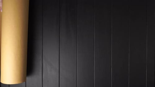 Hands Unrolling Antique World Map on Black Surface