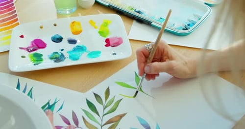Nahaufnahme Aquarellzeichnung auf Papier mit Pinsel, Palette und Farben, Blätter auf weißem Papier gemalt