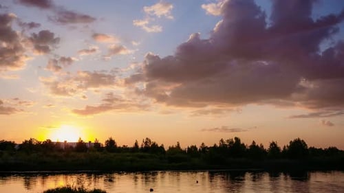 The Sun Sets Over the Horizon with the Forest Above the River. Summer Evening