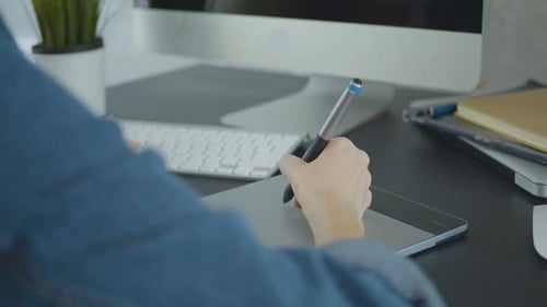 Designer Uses Stylus on Graphics Tablet at Desk
