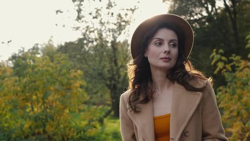 Stylish Woman Walking in the Park in Autumn