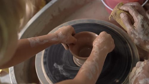 Child and Adult Creating Clay Pottery on Wheel