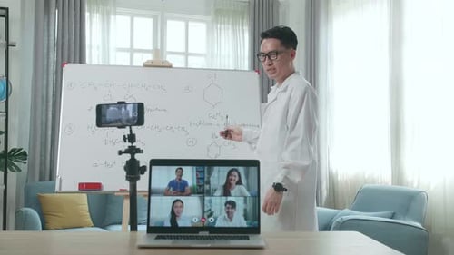 El profesor graba Vídeo por teléfono inteligente y tiene una videollamada en una computadora portátil mientras enseña químico en línea