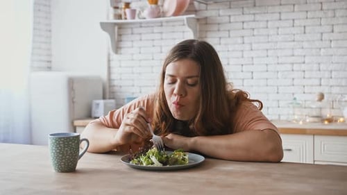 Woman Eats Healthy Salad at Kitchen Table