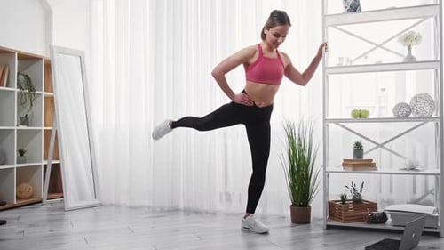 Young Woman Exercising at Home Doing Leg Raises