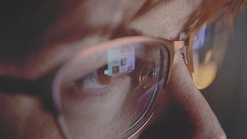A Woman with Glasses Looks at the Screen in the Evening Reflection in Glasses Close Up
