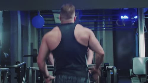A Sporty Man Runs on a Treadmill in the Gym