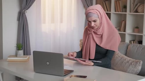 Woman Reviews Data at Desk Indoors