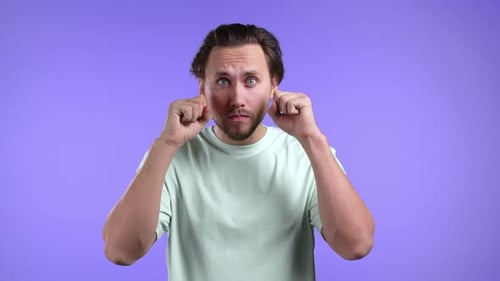 Young Man Cannot Believe His Eyes Rubs It and Peers More Closely at Camera on Purple Studio