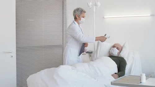 Doctor Checks Patient Temperature in Hospital Room