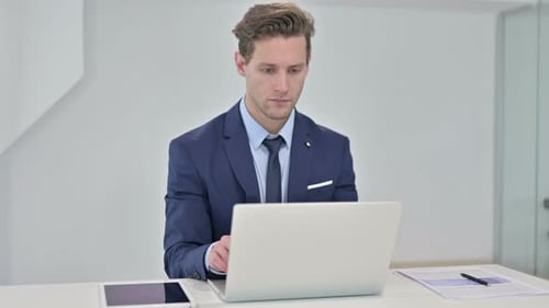 Focused Young Businessman Working on Laptop in Office