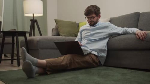 Young Adult Using Laptop Relaxing at Home