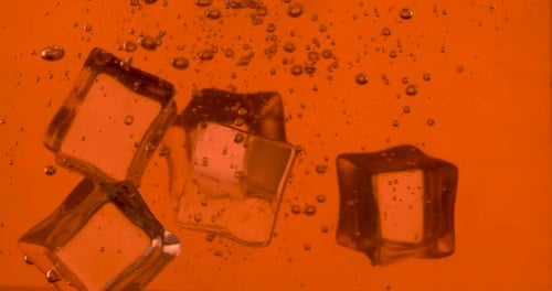 Ice Cubes Falling Into Orange Soda