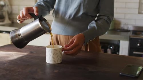Pouring coffee into a mug at home