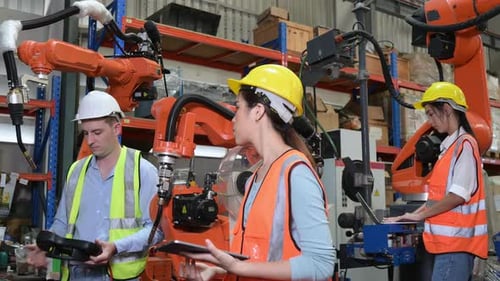 Männliche und weibliche Ingenieure inspizieren den kürzlich installierten Schweißroboter