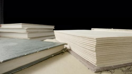 Camera Movement Along Open Book with White Paper Sheets and Old Books with Shabby Covers