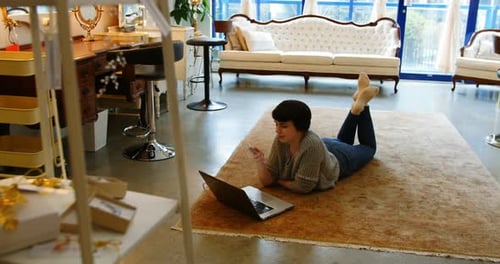 Woman Uses Laptop and Phone on Rug