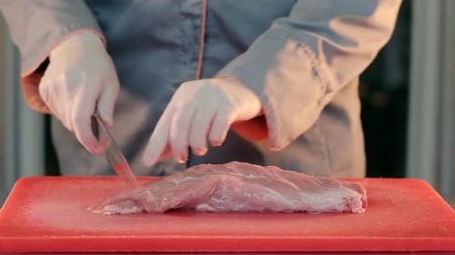Cutting Raw Meat with a Knife Close Up