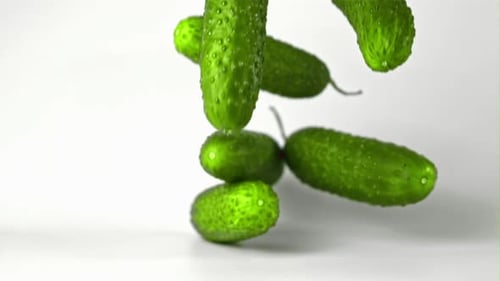 Falling Green Cucumbers Against White Background