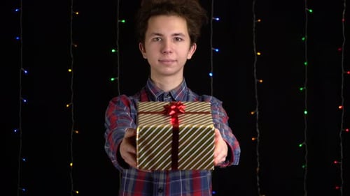 Young Adult Presents a Gift Box With Red Ribbon
