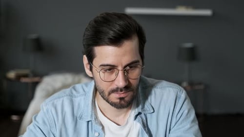 Close Up of a young Thoughtful European man with Glasses Working at a Computer at home