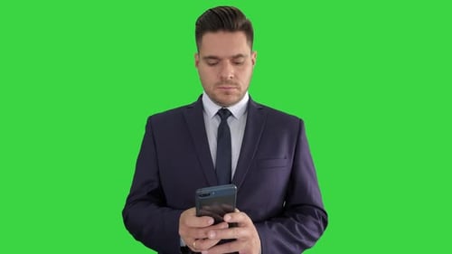 Serious Businessman Texting Message on His Phone on a Green Screen, Chroma Key.