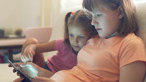Two Young Girls Using Tablet Together Indoors