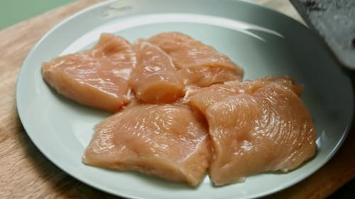 Gloved Hands Transferring Raw Chicken on Plate