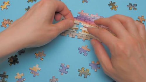 Unvollendete Puzzleteile auf blauem Hintergrund. Stelle Puzzle mit Dramatisch Himmel zusammen. Hände zusammenbauen