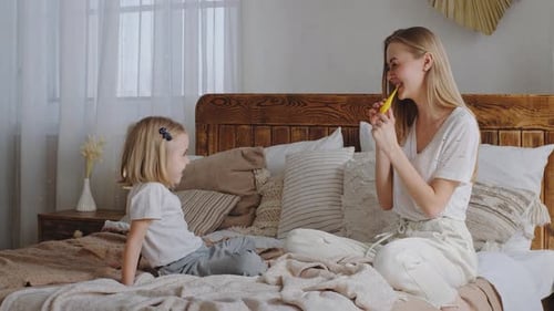 Woman Blowing up Balloon With Young Child Watching