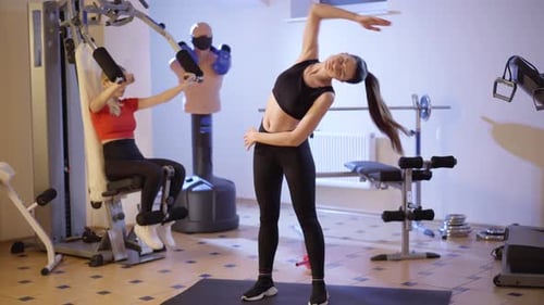 Two Women Exercising in a Bright Gym
