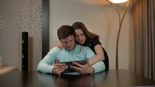 Affectionate Couple Using Tablet Device at Home