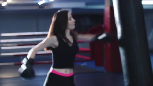 Junge Frau, die Boxen trainiert, geht dann zur Kamera und zeigt ihre Boxhandschuhe